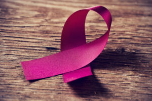 closeup of a pink ribbon, symbol of breast cancer awareness, on a rustic wooden surface